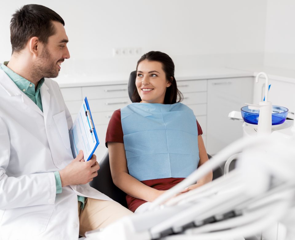 Dentist Talking To Female Patient At Dental Clinic